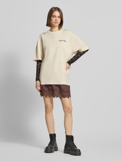 Frauenmodel trägt Oversized T-Shirt mit Statement-Print von REVIEW, Reine Baumwolle, Oversize-Fit, Rundhalsausschnitt, Damen T-Shirt, Rückenlänge 70 cm, Größe S, Ganzkörperansicht von vorne.