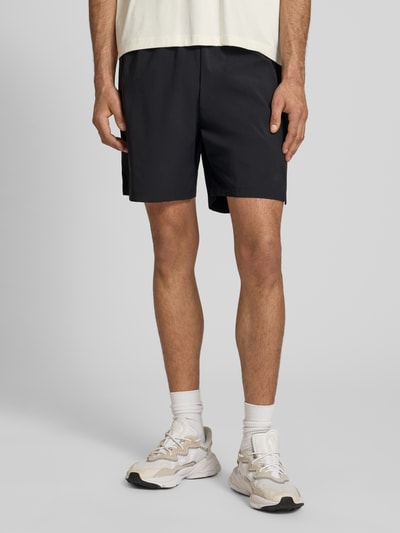 Männermodel trägt Regular Fit Shorts mit Tunnelzug von adidas Sportswear, Optik: Unifarben, Passform: Regular-Fit, Logo-Print, Kontraststreifen, Bundabschluss: elastisch mit Tunnelzug, seitliche Eingrifftaschen, Nahaufnahme Oberschenkel.