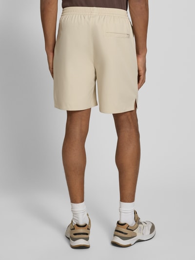 Männermodel trägt Shorts mit elastischem Bund Modell 'Raphael' von Les Deux in Beige, Material-Mix mit Stretch-Anteil, Regular-Fit, Ganzkörperansicht Rückansicht.