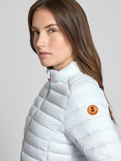 Kobiece modelka nosi Slim Fit Steppjacke gefüttertem Stehkragen Modell 'Carly' od SAVE THE DUCK, biała, steppowana faktura, krój slim fit, długość tyłu w rozmiarze S: 58 cm, szerokość ramion w rozmiarze S: 39 cm, szerokość klatki piersiowej w rozmiarze S: 45 cm, długość rękawa w rozmiarze S: 61 cm, z przodu widok zbliżony na górną część ciała.