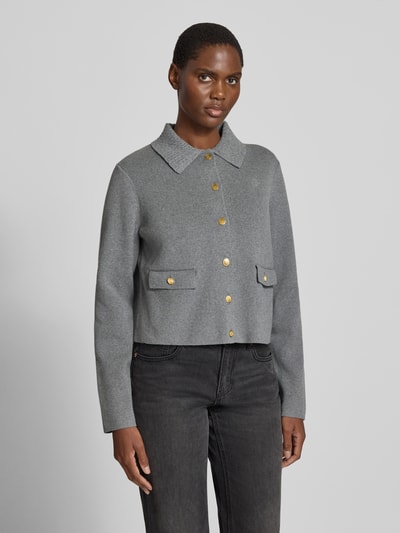 Frauenmodel trägt Strickjacke aus Baumwoll-Woll-Mix von Tommy Hilfiger in Grau mit Zierknöpfen, Kragen und Brusttasche, Ganzkörperansicht von vorne.