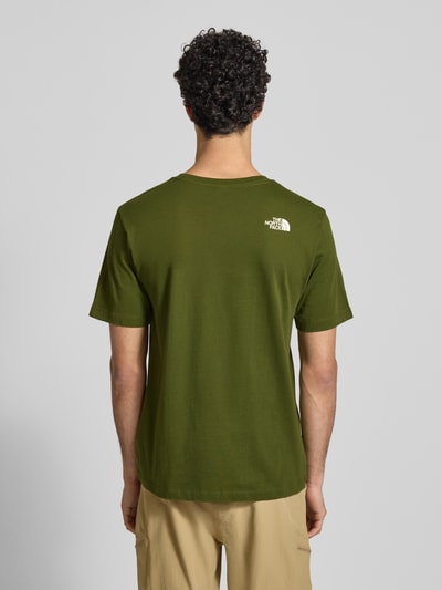 Männermodel trägt Regular Fit T-Shirt aus reiner Baumwolle Modell 'MOUNTAIN LINE' von The North Face in Oliv mit Label-Print, Rückenlänge 70 cm, Rückenansicht Ganzkörperansicht.