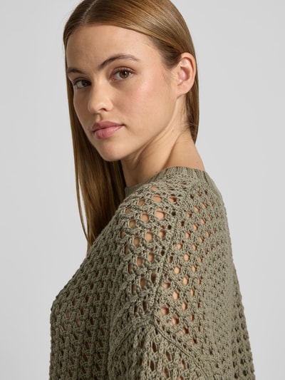Frauenmodel trägt Relaxed Fit Pullover mit Lochmuster von Juvia aus reiner Baumwolle in Khaki, Nahaufnahme Oberkörper.