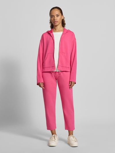 Frauenmodel trägt Regular Fit Sweatjacke mit Modal-Anteil von Christian Berg Woman in Pink, Kapuze, Reißverschluss, Känguru-Tasche, Ganzkörperansicht von vorne.