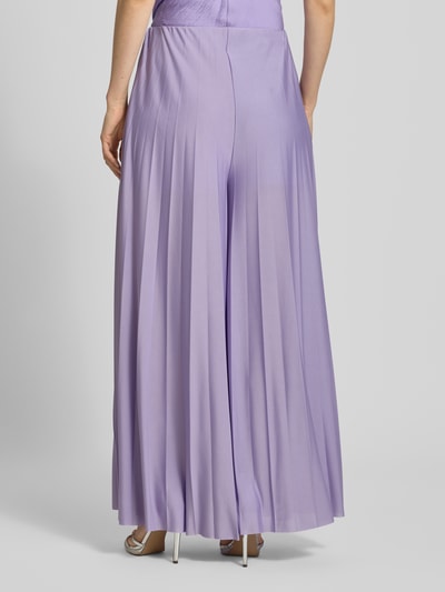 Frauenmodel trägt Wide Fit Stoffhose in Falten-Optik Modell 'Samantha' von GUIDO MARIA KRETSCHMER WOMAN, lila, fließender Stoff, Ganzkörperansicht Rückansicht, Bundweite 36 cm, Innenbeinlänge 75 cm.