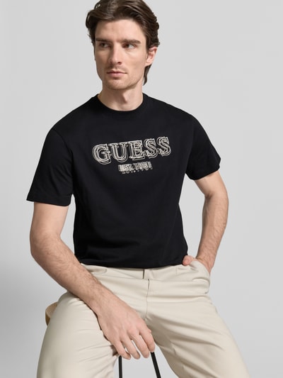 Męski model nosi T-shirt mit Label-Detail od GUESS, bawełna, krój regular fit, okrągły dekolt, długość tyłu 69 cm, Ganzkörperansicht von przodu.