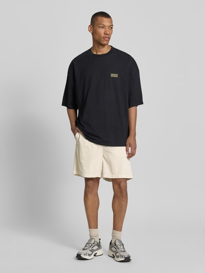 Männermodel trägt Shorts mit elastischem Bund Modell 'PADOW' von American Vintage aus Reine Baumwolle, Loose-Fit, Cremefarbe, Ganzkörperansicht von vorne.