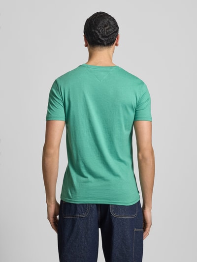 Männermodel trägt Slim Fit T-Shirt aus Baumwoll-Mix Modell 'JASPE HERITAGE' von Tommy Jeans in Melange-Optik, Ganzkörperansicht Rückansicht.