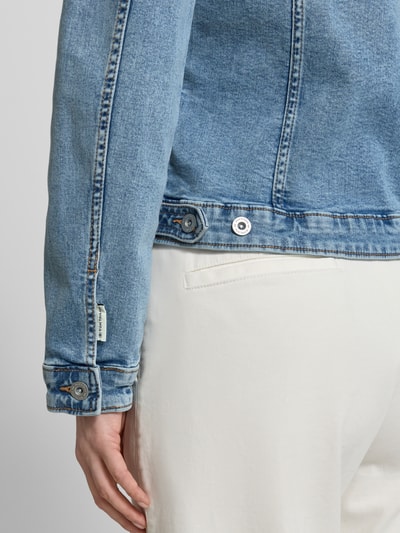 Frauenmodel trägt Slim Fit Jeansjacke aus Baumwoll-Mix von Tom Tailor in Denim-Optik mit Label-Prägung, Twill-Struktur, Detailaufnahme.