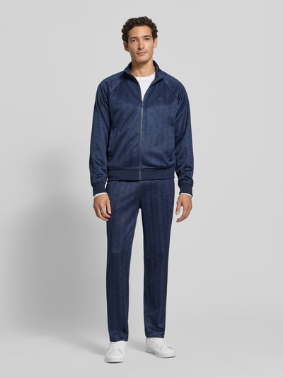 Männermodel trägt Regular Fit Sweathose aus mit Logo-Print von Lacoste in Dunkelblau, feine Struktur, Ganzkörperansicht von vorne, Herren Sweathose von Lacoste.