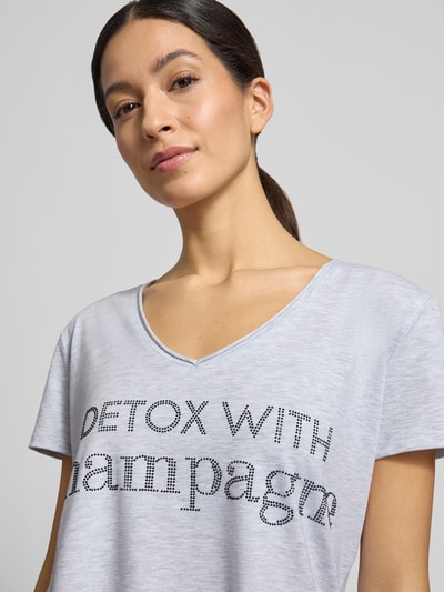 Frauenmodel trägt T-Shirt mit Label-Detail von miss goodlife aus Baumwoll-Elasthan-Mix in Hellgrau, V-Ausschnitt, lockerer Schnitt, Nahaufnahme Oberkörper