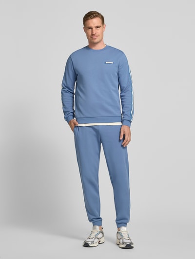 Männermodel trägt hellblaue Sweatpants mit elastischem Bund von EA7 Emporio Armani aus Baumwoll-Mix in Regular Fit, Ganzkörperansicht von vorne.