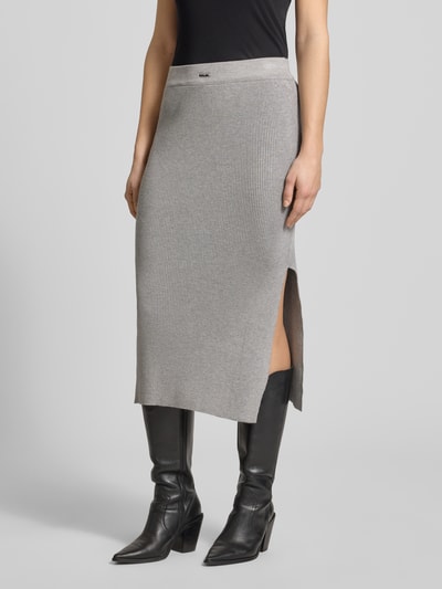 Kobiece modelka nosi Strickrock mit Label-Patch und elastischem Bund von Karo Kauer, mieszanka wiskozy, dopasowany krój, spódnica midi, drobne prążkowanie, naszywka z logo, elastyczny pas, szerokość w rozmiarze S: 37 cm, całkowita długość: 80 cm, kolor szary, gładka faktura, widoczne rozcięcie, zdjęcie całej sylwetki z przodu.