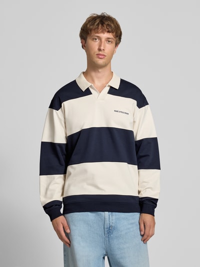 Männermodel trägt Relaxed Fit Troyer aus reiner Baumwolle von Marc O'Polo DENIM in Creme und Dunkelblau, breite Blockstreifen, Ganzkörperansicht von vorne.
