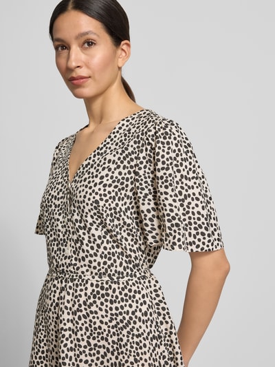 Frauenmodel trägt Minikleid aus Viskose mit kurzer Knopfleiste Modell 'GRACE' von Vila, heller Stoff mit schwarzen Punkten, taillierter Schnitt, V-Ausschnitt, Bindegürtel, reine Viskose, Nahaufnahme Oberkörper.