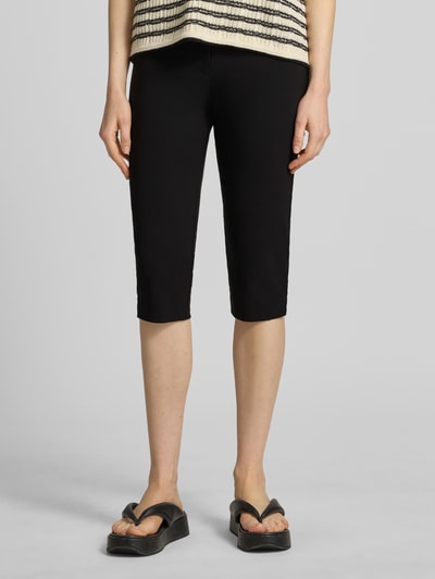 Kobiece modelka nosi Carprihose aus Viskose-Mix mit seitlichen Schlitzen od Jake*s Casual, czarne, krój slim fit, lekko elastyczne, boczne rozcięcia, szerokość w rozmiarze 36: 36 cm, długość nogawki od wewnątrz w rozmiarze 36: 44 cm, zdjęcie całej sylwetki z przodu.
