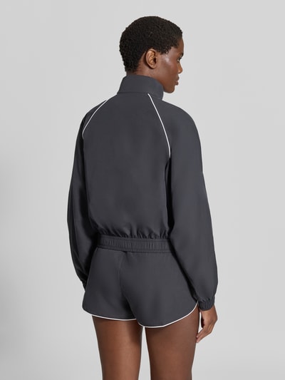Frauenmodel trägt Relaxed Fit Trainingsjacke mit Logo-Patch von Lacoste, dunkelgraue Farbe, glatte Textur, Damen Trainingsjacke von Lacoste Sport, Ganzkörperansicht Rückansicht.