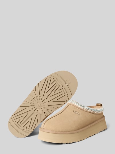 Produktfoto, Hausschuhe mit Label-Detail Modell 'Tazz' von UGG aus beschichtetem Leder-Mix in Beige, strukturierte Sohle, abgerundete Spitze, Absatzhöhe 4 cm, Schafthöhe 3 cm, Schaftweite 14 cm.