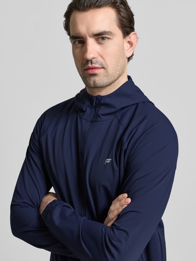 Männermodel trägt Regular Fit Jacke mit Logo-Print von Fabletics in Dunkelblau, elastischer Material-Mix, Nahaufnahme Oberkörper.