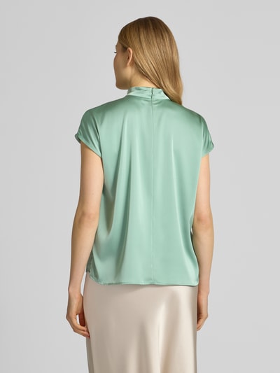 Frauenmodel trägt Blusenshirt mit Stehkragen von Jake*s Collection, Material-Mix mit Stretch-Anteil, Regular-Fit, Rückseitiger Reißverschluss, Rückenlänge 59 cm in Größe 38, zarte Mintfarbe mit glatter Textur, Ganzkörperansicht Rückansicht.