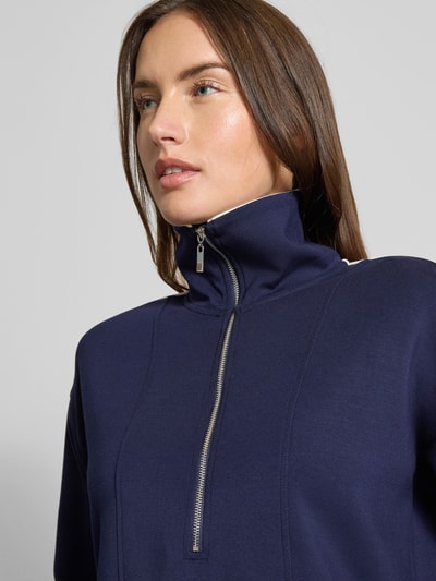 Frauenmodel trägt Sweatshirt mit kurzem Reißverschluss von Christian Berg Woman, dunkles Blau, Material-Mix mit Modal-Anteil, Nahaufnahme Oberkörper.