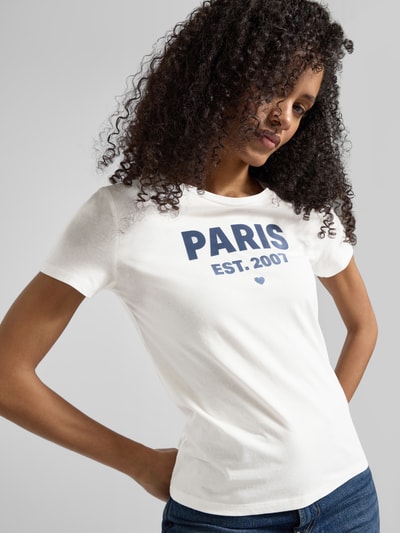 Frauenmodel trägt Regular Fit T-Shirt aus reiner Baumwolle von Tom Tailor Denim, Optik: Unifarben, Applikation: weicher Schriftzug-Print, Rundhals, Kurzarm, Material: reine Baumwolle, Ganzkörperansicht von vorne.