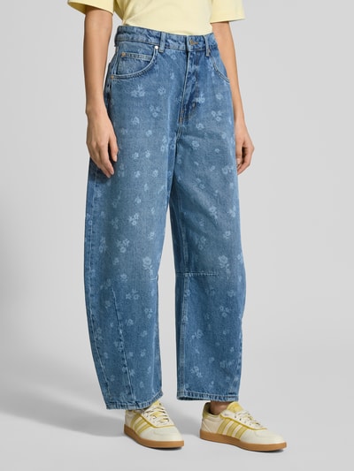 Frauenmodel trägt Barrel Fit Jeans aus reiner Baumwolle Modell 'JO1' von Essentiel Antwerp in Denim-Optik mit Kontrast-Nähten, Label-Stitching-Applikation, 5-Pocket-Design, Knopf und verdecktem Reißverschluss, mittleres Blau mit floralen Mustern, texturiert, Ganzkörperansicht von vorne.