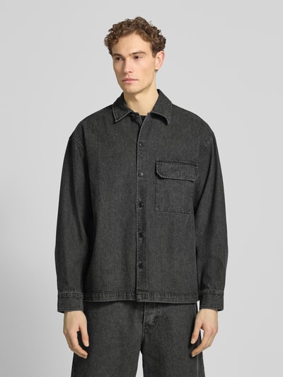 Männermodel trägt Relaxed Fit Hemdjacke mit Brusttasche Modell 'David' von Wood Wood aus Baumwoll-Mix in Schwarz, Nahaufnahme Oberkörper.
