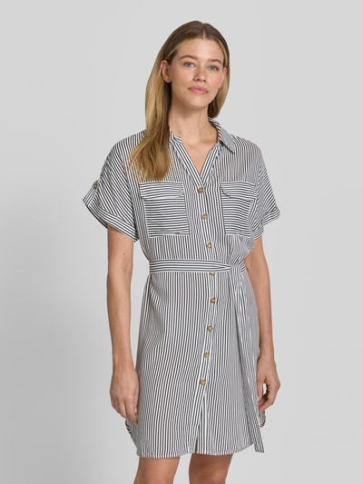 Kobiece modelka nosi Fließendes Freizeitkleid aus reiner Viskose Modell 'BUMPY' od Vero Moda, efekt: jednolity kolor, krój: swobodny, długość: mini, dekolt w serek, pas na plecach, listwa guzikowa, rękaw: krótki, popelina, materiał: czysta wiskoza. Ganzkörperansicht z przodu.