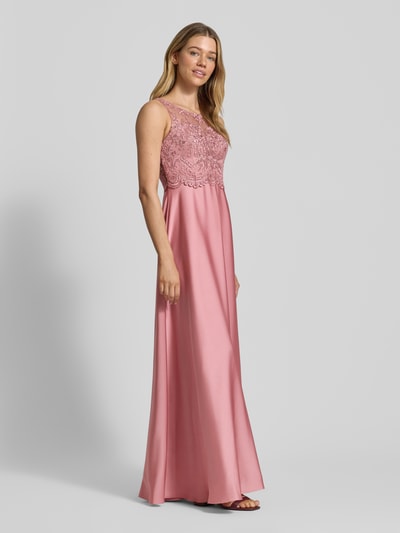 Frauenmodel trägt Abendkleid mit floralem Spitzenbesatz von Laona in Rosa, taillierte Passform, semitransparente Optik, ganzkörperansicht von vorne. Rückenlänge Größe 36: 142 cm, Brustweite: 32 cm, ärmelloses Design, Ziersteinbesatz.