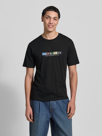 Männermodel trägt schwarzes T-Shirt aus Bio-Baumwolle Modell 'NANTUCKET' von Jack & Jones mit Label-Print, gerader Schnitt, Nahaufnahme Oberkörper.