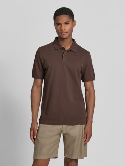 Męski model nosi Regular Fit Poloshirt aus reiner Baumwolle od s.Oliver RED LABEL, efekt: jednolity kolor, krój regular fit, wyhaftowane logo, kołnierzyk polo, dekolt w serek, listwa guzikowa, krótki rękaw, zakończenie rękawów: prążkowane, wykończenie: z rozcięciami po bokach, wykończenie materiału: pika, materiał: bawełna, kolor brązowy, klasyczny styl, widok całej sylwetki z przodu.