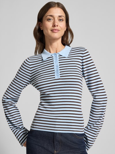 Frauenmodel trägt Poloshirt aus Viskose-Mix Modell 'Fannya' von Neo Noir, schmal gestreift in Hellblau und Braun, Ganzkörperansicht von vorne. Damen Longsleeve, Slim Fit, Allover-Look, Polokragen, Knopfleiste, Rückenlänge bei Größe 36: 55 cm.