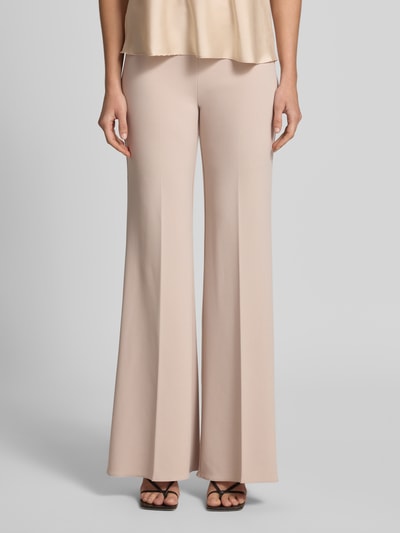 Frauenmodel trägt Stoffhose mit Bügelfalte und Reißverschluss von Rinascimento in Beige, Flared Fit, glatte Stretch-Oberfläche, Ganzkörperansicht von vorne.