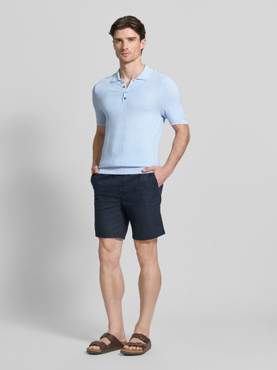 Mannelijk model draagt lichtblauw Slim Fit Poloshirt met viscose-aandeel model 'Gio' van CINQUE, polokraag, rechte lijnen, effen kleur, gecombineerd met donkere korte broek, context heren poloshirt, viscose-mix, slim fit, polokraag, ruglengte maat M 71 cm, volledige lichaamsaanzicht van voren.