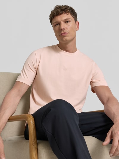 Männermodel trägt Relaxed Fit T-Shirt aus Baumwoll-Mix Modell 'TCHUP' von BOSS Orange, Optik: Unifarben, Label-Print, Nahaufnahme Oberkörper.