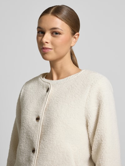 Kobiece model prezentuje Jacke mit Knopfleiste Modell 'ADA' od Vila, krój regular fit, miękki teddyfell, okrągły dekolt, zapięcie na guziki, kieszenie boczne, długość tyłu w rozmiarze 36: 57 cm, szerokość ramion w rozmiarze 36: 41 cm, szerokość w biuście w rozmiarze 36: 54 cm, długość rękawa w rozmiarze 36: 57 cm, kremowa faktura, zbliżenie na górną część ciała.