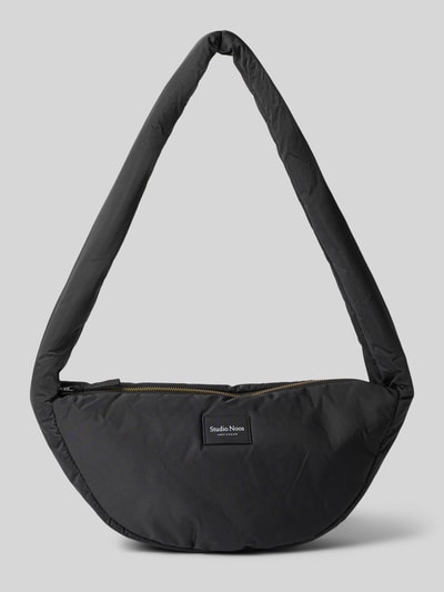 Produktfoto, schwarze Schultertasche Shoulder Bag mit Logo-Detail Modell 'Puffy' von Studio Noos, sichtbare Reißverschluss-Textur, weiche Haptik, Maße ca. 38x20x9 cm, gepolsterter Schulterriemen etwa 86 cm, minimalistisches Design auf grauem Hintergrund.