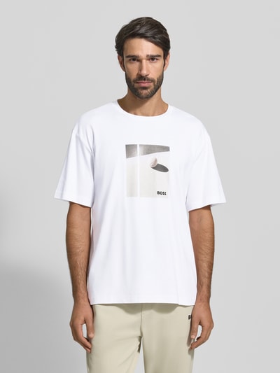 Męski model nosi Relaxed Fit T-Shirt aus reiner Baumwolle Modell 'JOIN' od BOSS Green, białe, prosty nadruk, krótki rękaw, widok całej sylwetki z przodu.