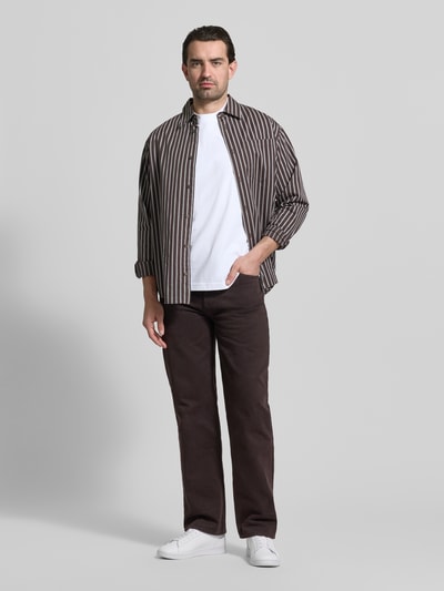 Männermodel trägt Regular Fit T-Shirt aus reiner Baumwolle von MCNEAL, weiß, kombiniert zu gestreiftem Hemd und dunkler Hose, Ganzkörperansicht von vorne.