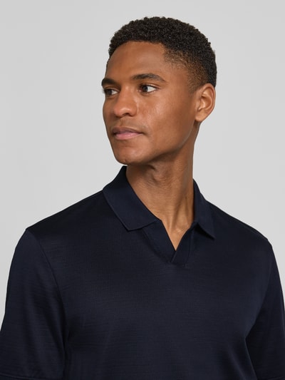 Männermodel trägt Regular Fit Poloshirt mit Strukturmuster von bugatti aus Reine Baumwolle, Polokragen, V-Ausschnitt, Label-Detail, Nahaufnahme Oberkörper.