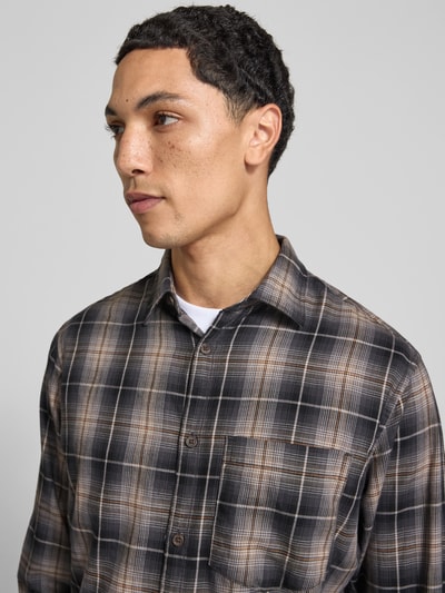 Männermodel trägt Slim Fit Freizeithemd aus reiner Baumwolle Modell 'James' von JACK & JONES, kariert, Nahaufnahme Oberkörper.