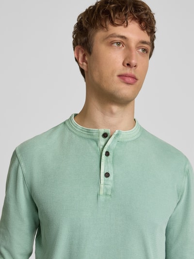 Męski model nosi Longsleeeve mit Knopfleiste od Superdry w kolorze miętowozielonym, czysta bawełna, krój regular fit, okrągły dekolt, długość tyłu w rozmiarze M 72 cm, zbliżenie na górną część ciała
