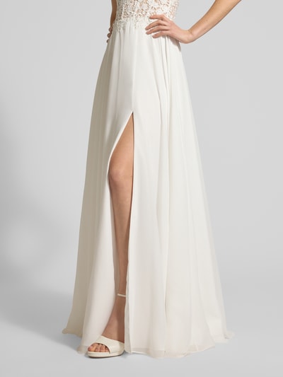 Frauenmodel trägt Regular Fit Brautkleid mit floralem Spitzenbesatz von Luxuar, semitransparent, schulterfrei, Nahtreißverschluss, Blickdichter Unterrock, Rock mit Schlitz, cremefarbene Optik, Ganzkörperansicht von vorne.