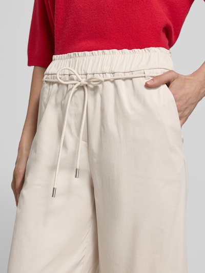 Vrouwenmodel draagt Culotte met elastische tailleband en bindriem van Marc Cain in crèmekleur, wijde pijpen, katoenmix met viscose, detailopname taille en heupen