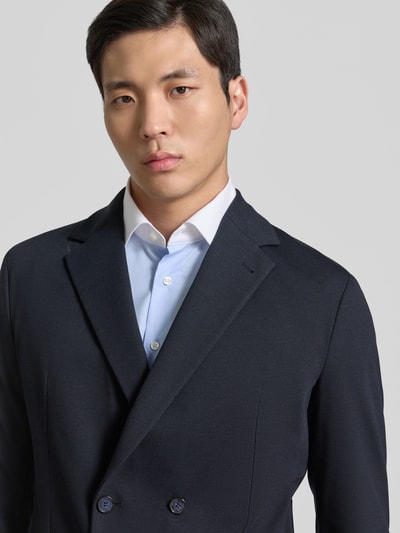 Męski model nosi Slim Fit Sakko mit Reverskragen Modell 'BERTUE' od CINQUE, granatowy, gładka tekstura, zbliżenie na górną część ciała. Krój slim fit, dwurzędowy, z naszywanymi kieszeniami, długość pleców w rozmiarze 50: 73 cm, szerokość ramion w rozmiarze 50: 43 cm, długość rękawa w rozmiarze 50: 62 cm.