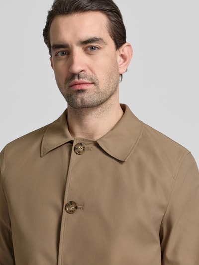 Männermodel trägt Mantel mit Knopfleiste von MCNEAL in Beige mit Kentkragen und lockerer Passform, Nahaufnahme Oberkörper.