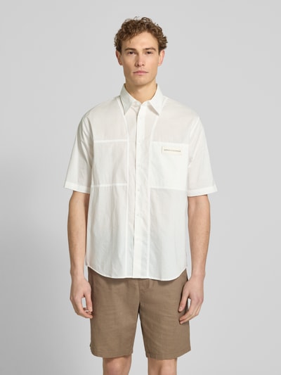 Männermodel trägt Boxy Fit Freizeithemd mit Label-Patch von ARMANI EXCHANGE in Weiß, reine Baumwolle, Kentkragen, Knopfleiste, Brusttasche, Ganzkörperansicht von vorne.