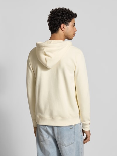 Männermodel trägt Regular Fit Sweatjacke mit Logo-Stitching von Superdry aus Baumwoll-Mix in Creme mit Kapuze, Ganzkörperansicht Rückansicht.