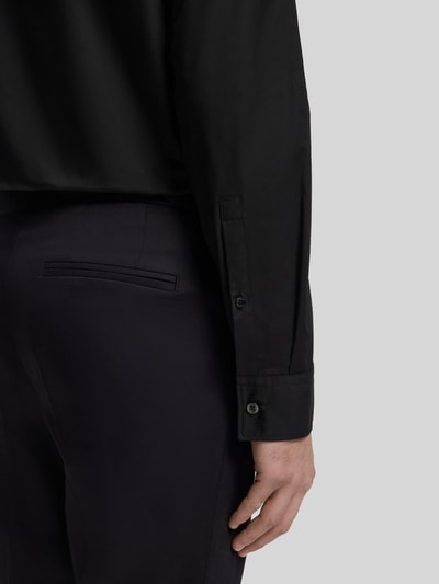 Männermodel trägt Slim Fit Freizeithemd aus Baumwoll-Mix Modell 'ERMO' von HUGO in Schwarz, Detailaufnahme Ärmel und Rückenpasse.